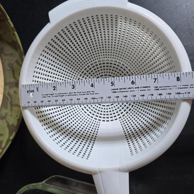Two large serving bowls a glass cake pan, strainer and 5 square glass containers with cork stoppers