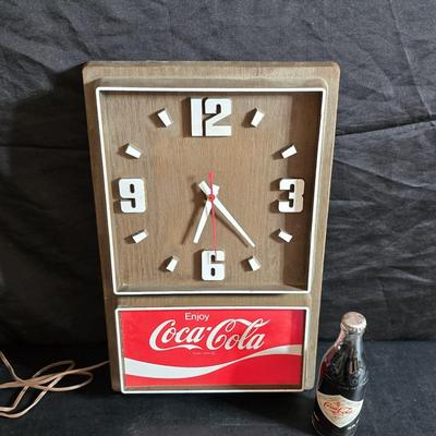 Working 1970s Coca-Cola wall clock with a faux wood grain plastic frame and a commemorative Coca-Cola bottle from the 1984 Summer...