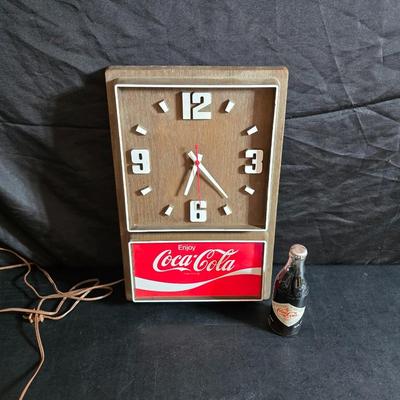 Working 1970s Coca-Cola wall clock with a faux wood grain plastic frame and a commemorative Coca-Cola bottle from the 1984 Summer...