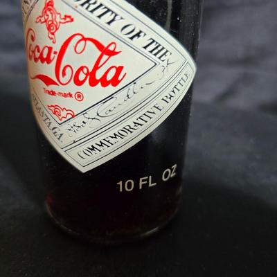 Working 1970s Coca-Cola wall clock with a faux wood grain plastic frame and a commemorative Coca-Cola bottle from the 1984 Summer...