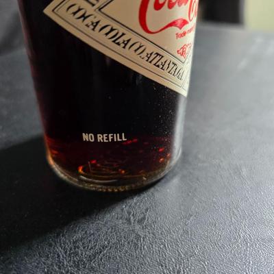 Working 1970s Coca-Cola wall clock with a faux wood grain plastic frame and a commemorative Coca-Cola bottle from the 1984 Summer...
