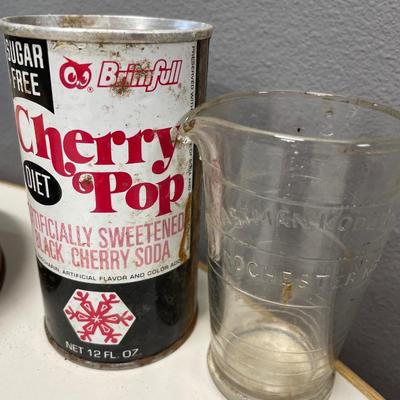 Fruitcake tin, cherry pop can and Eastman Kodak Co glass beaker