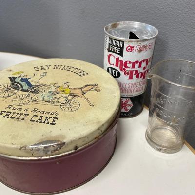 Fruitcake tin, cherry pop can and Eastman Kodak Co glass beaker