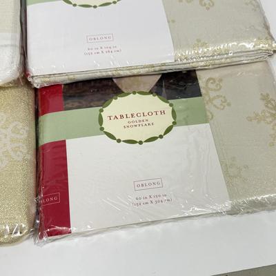 LOT 121: 4 NIP Oblong Golden Plaid and Snowflake Table Cloths