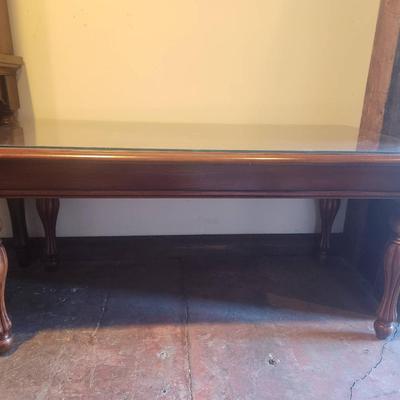 Sale Photo Thumbnail #24: Rectangular wooden coffee table featuring a protective glass top overlay. The table displays decorative inlay detailing on its surface and rests on four sturdy turned legs. Condition appears to be good with minimal signs of wear. Suitable for both functio
