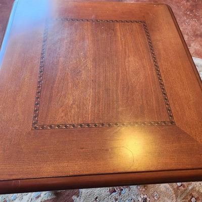 Sale Photo Thumbnail #32: Square side table crafted from cherry wood, featuring a 2x2x2. The tabletop includes a decorative inlay detail around the center panel. Supported by four intricately carved wooden legs. Suitable for various interior decor styles.