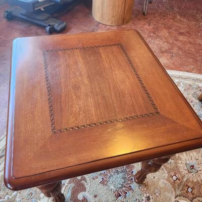 Sale Photo Thumbnail #30: Square side table crafted from cherry wood, featuring a 2x2x2. The tabletop includes a decorative inlay detail around the center panel. Supported by four intricately carved wooden legs. Suitable for various interior decor styles.