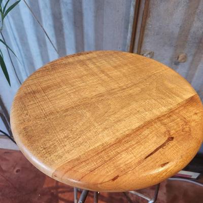 Sale Photo Thumbnail #39: Three bar stools featuring round seats crafted from mango wood. The stools are mounted on sturdy metal bases with an adjustable screw mechanism for height changes. The base design incorporates a minimalist aesthetic, with footrests for added comfort. Thes