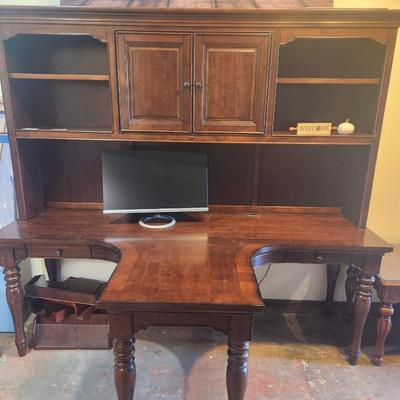 Sale Photo Thumbnail #44: Dual desk constructed from cherry wood, featuring a top hutch with cabinet doors and open shelving for storage and display. The desk includes a central cutout and two working areas on either side, supported by turned wooden legs. Ideal for functional work