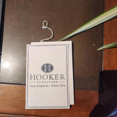 Sale Photo Thumbnail #52: Hooker desk crafted from cherry wood, measuring 6 feet in length, 3 feet in width, and 2.6 feet in height. Features include a glass top for added protection, multiple drawers for storage, and elegant carved details. Labeled with Hooker Furniture branding,