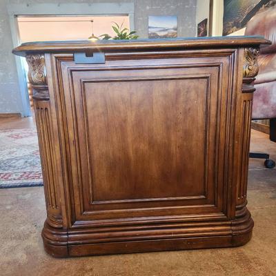 Sale Photo Thumbnail #82: Hooker desk crafted from cherry wood, measuring 6 feet in length, 3 feet in width, and 2.6 feet in height. Features include a glass top for added protection, multiple drawers for storage, and elegant carved details. Labeled with Hooker Furniture branding,