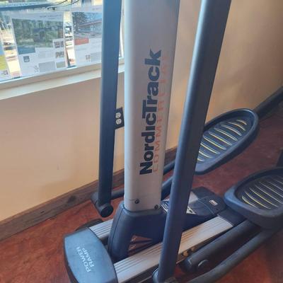 Sale Photo Thumbnail #154: NordicTrack elliptical trainer featuring a built-in display panel for workout tracking. Equipped with foot pedals and upper-body resistance handles. The unit has a sturdy frame and rolling wheels for easy mobility. Appears to be in well-maintained conditi