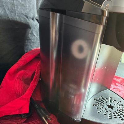 Keurig coffee maker with pod caddy - a red apron - and several Christmas themed mugs.