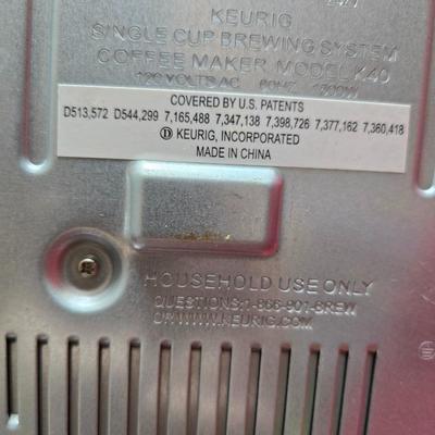 Keurig coffee maker with pod caddy - a red apron - and several Christmas themed mugs.