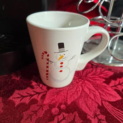 Keurig coffee maker with pod caddy - a red apron - and several Christmas themed mugs.