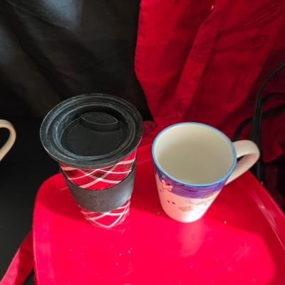 Keurig coffee maker with pod caddy - a red apron - and several Christmas themed mugs.
