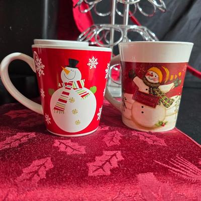 Keurig coffee maker with pod caddy - a red apron - and several Christmas themed mugs.
