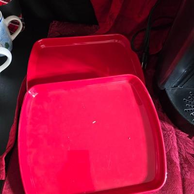 Keurig coffee maker with pod caddy - a red apron - and several Christmas themed mugs.