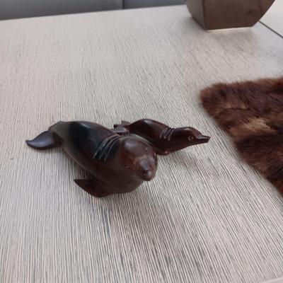 FAUX ORCHID IN CERAMIC POT, CARVED WOODEN SEALS AND AN ANIMAL PELT