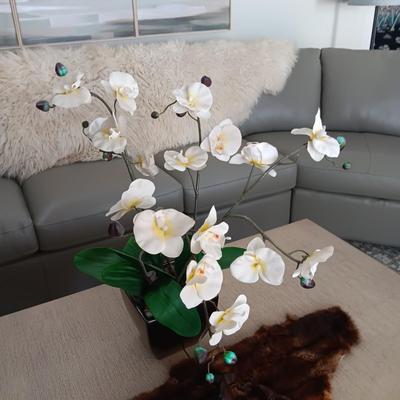 FAUX ORCHID IN CERAMIC POT, CARVED WOODEN SEALS AND AN ANIMAL PELT