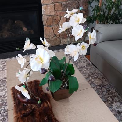 FAUX ORCHID IN CERAMIC POT, CARVED WOODEN SEALS AND AN ANIMAL PELT
