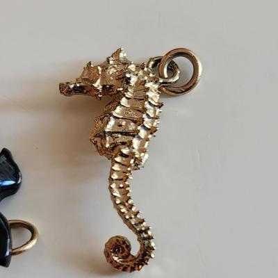 Sale Photo Thumbnail #116: This auction lot is for Four Sweet Charms.  This charms where in the bottom of a small dresser jewelry box in a recent estate. There is a small carved white whale, a carved stone turtle, a sea horse and a gold-tone heart locket in this group.