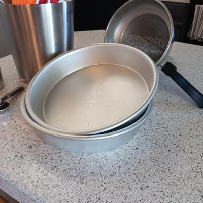 KITCHEN UTENSILS IN A STAINLESS STEEL HOLDER, SIEVE, CAKE PANS, MEASURING CUPS AND SPOONS