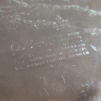 Two amber glass cake pans Fire King - Pyrex and two brand new metal bread loaf pans with a poppy flower tablecloth