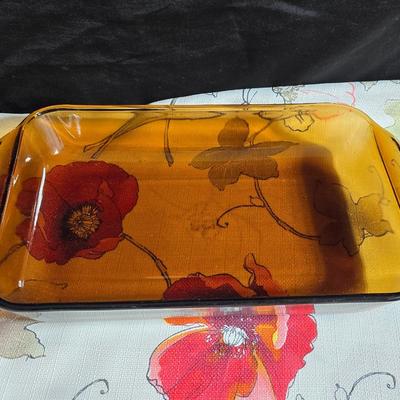 Two amber glass cake pans Fire King - Pyrex and two brand new metal bread loaf pans with a poppy flower tablecloth