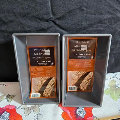 Two amber glass cake pans Fire King - Pyrex and two brand new metal bread loaf pans with a poppy flower tablecloth