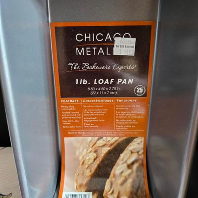 Two amber glass cake pans Fire King - Pyrex and two brand new metal bread loaf pans with a poppy flower tablecloth