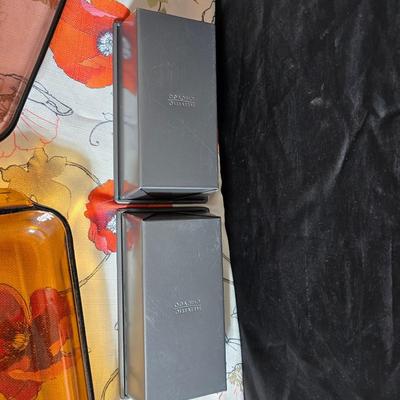 Two amber glass cake pans Fire King - Pyrex and two brand new metal bread loaf pans with a poppy flower tablecloth