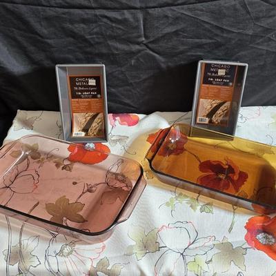 Two amber glass cake pans Fire King - Pyrex and two brand new metal bread loaf pans with a poppy flower tablecloth
