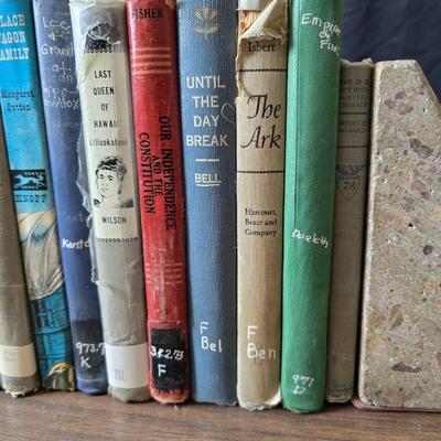 Wedge-shaped fossil stone bookends with a collection of vintage books