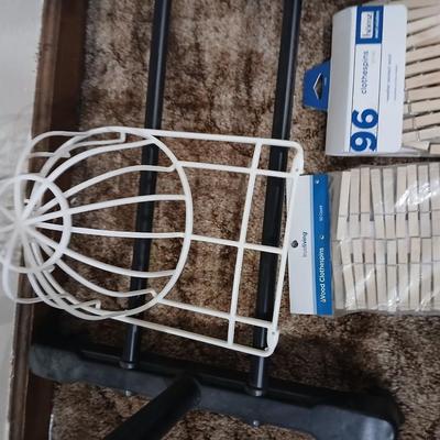 Portable clothes rack with packages of brand-new and opened clothes pins and a baseball cap cleaning tool