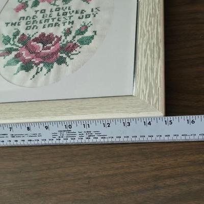 Two framed cross stitch wall art with a collection of pretty doilies