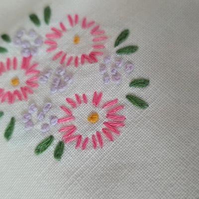 Two framed cross stitch wall art with a collection of pretty doilies