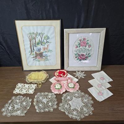 Two framed cross stitch wall art with a collection of pretty doilies
