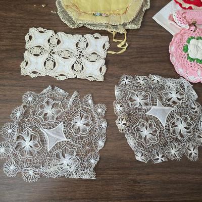 Two framed cross stitch wall art with a collection of pretty doilies