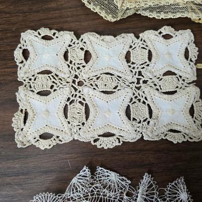 Two framed cross stitch wall art with a collection of pretty doilies