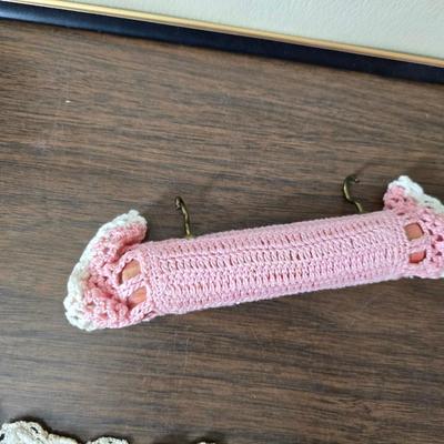 Two framed cross stitch wall art with a collection of pretty doilies