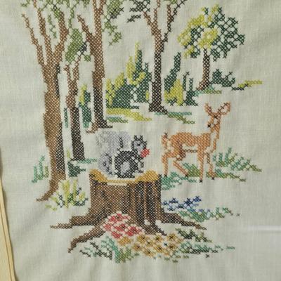 Two framed cross stitch wall art with a collection of pretty doilies