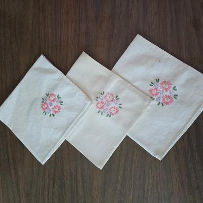 Two framed cross stitch wall art with a collection of pretty doilies