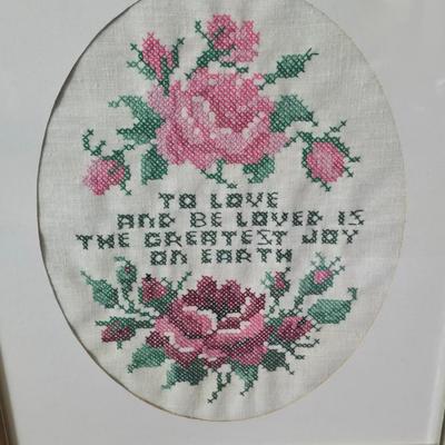 Two framed cross stitch wall art with a collection of pretty doilies