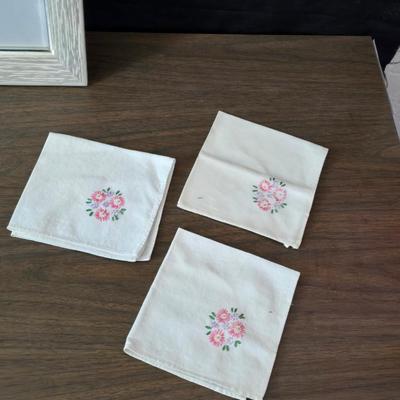 Two framed cross stitch wall art with a collection of pretty doilies