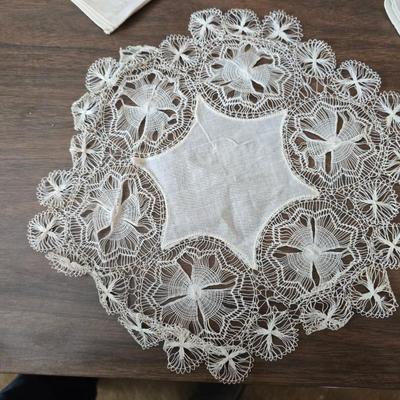 Two framed cross stitch wall art with a collection of pretty doilies