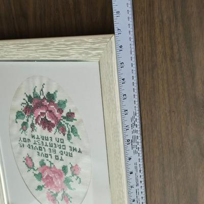 Two framed cross stitch wall art with a collection of pretty doilies