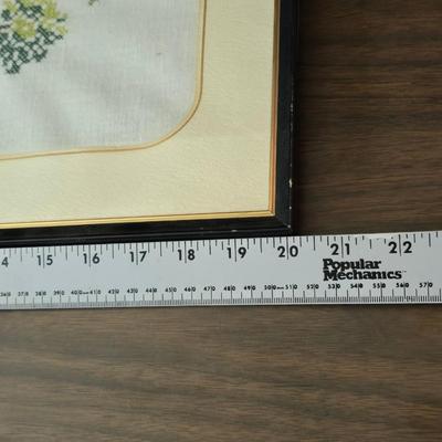 Two framed cross stitch wall art with a collection of pretty doilies