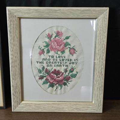 Two framed cross stitch wall art with a collection of pretty doilies