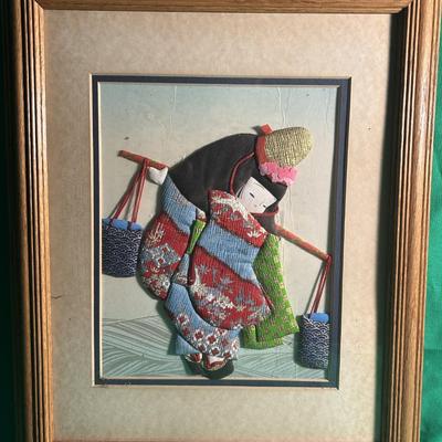 Sale Photo Thumbnail #19: Framed artwork depicting a Geisha figure, created with richly layered and colorful fabrics to form an intricate three-dimensional effect. The figure is dressed in traditional Japanese attire and carrying two buckets on a pole. The art is framed in a woode